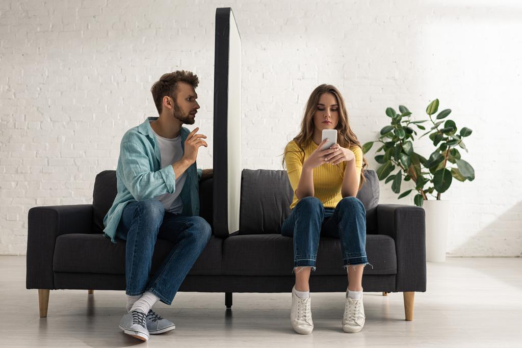 Mies istuu lähellä mallia älypuhelimen ja koukussa tyttöystävä chattailuun sohvalla
  - Valokuva, kuva