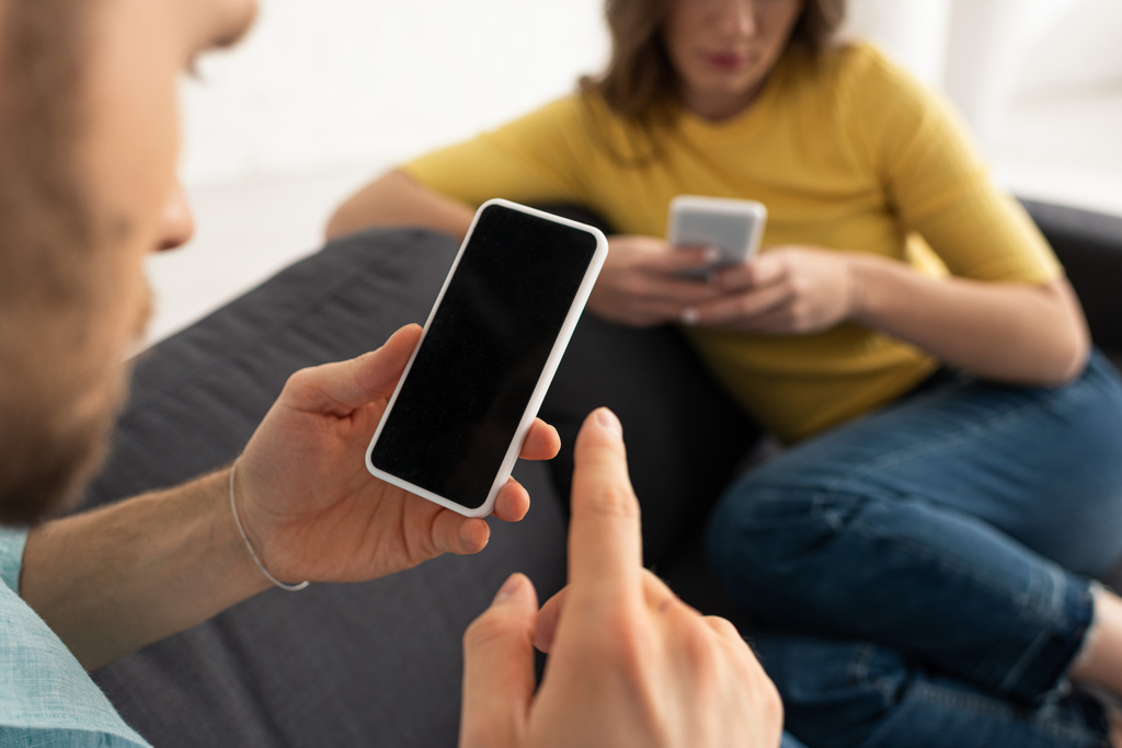 Вибірковий фокус залежного чоловіка за допомогою смартфона біля дівчини на дивані
  - Фото, зображення