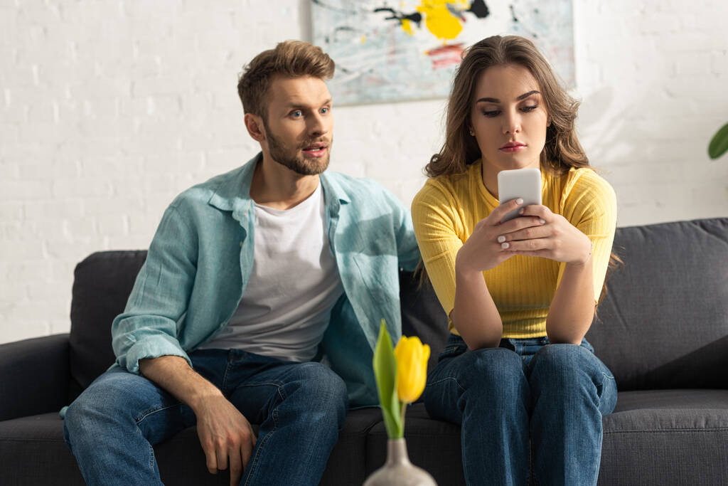 Valikoiva painopiste mies istuu lähellä älypuhelin riippuvainen tyttö sohvalla kotona
  - Valokuva, kuva
