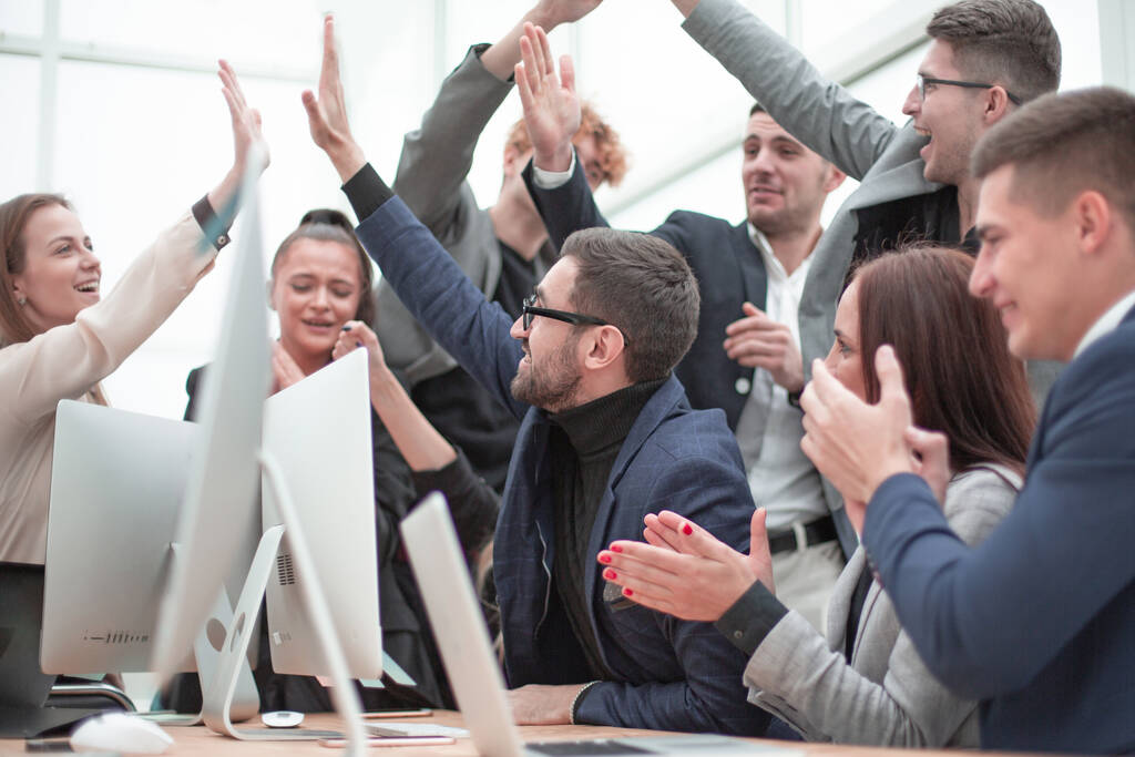 Счастливая рабочая группа аплодирует возле рабочего стола
 - Фото, изображение
