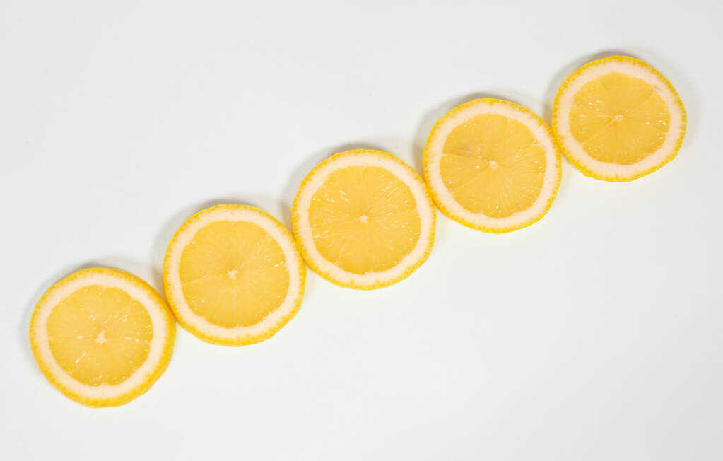 Slices of ripe juicy lemon lie diagonally on a white isolated background - Photo, Image