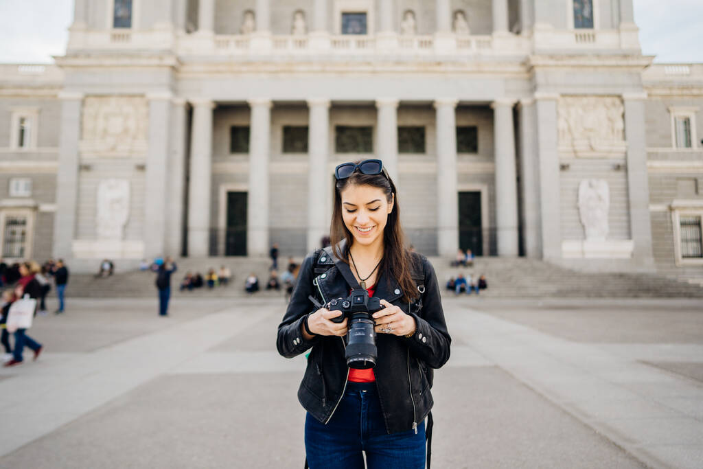 Női turista tartja kamera előtt mérföldkő épület Madrid, Spanyolország.Női fotós.Építészet és mérföldkő Madrid.Utazási fénykép.Blogger életmód - Fotó, kép