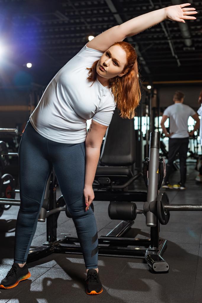 pretty, overweight girl warming up while doing side tilt exercise  - Photo, Image
