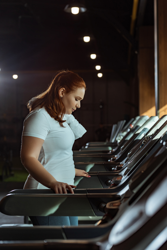concentrated overweight girl training on treadmill in gym - Photo, Image