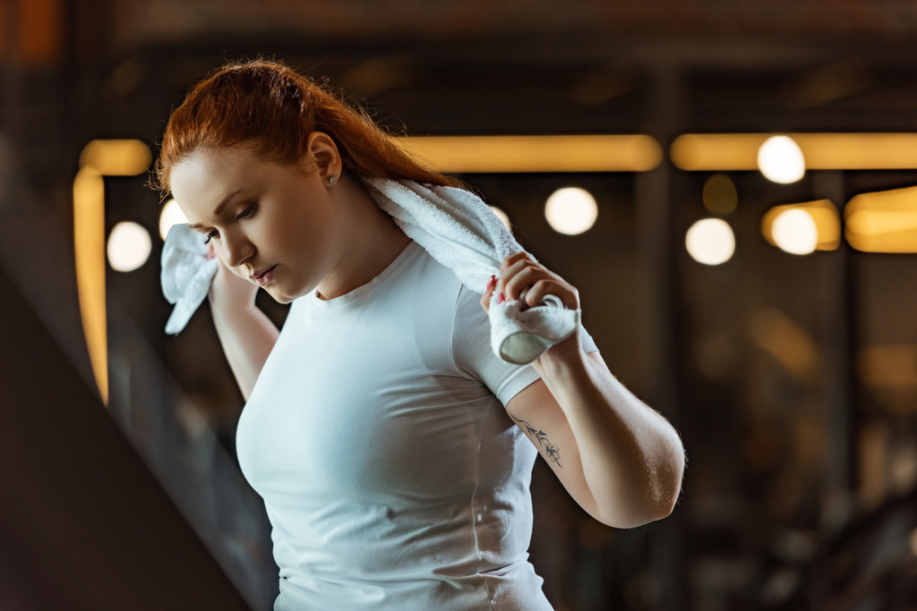bonita, chica con sobrepeso haciendo ejercicio en el gimnasio mientras sostiene la toalla
 - Foto, Imagen