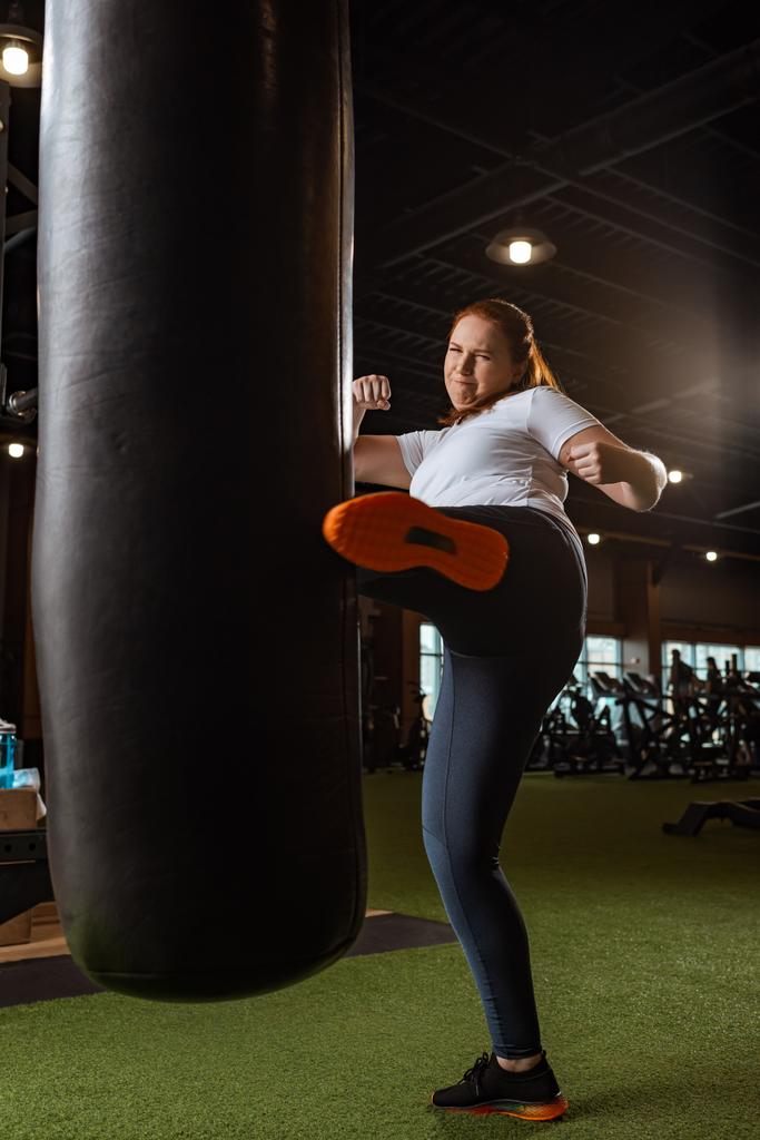 energinen ylipainoinen tyttö potkiminen nyrkkeilysäkki jalka kuntosalilla
 - Valokuva, kuva