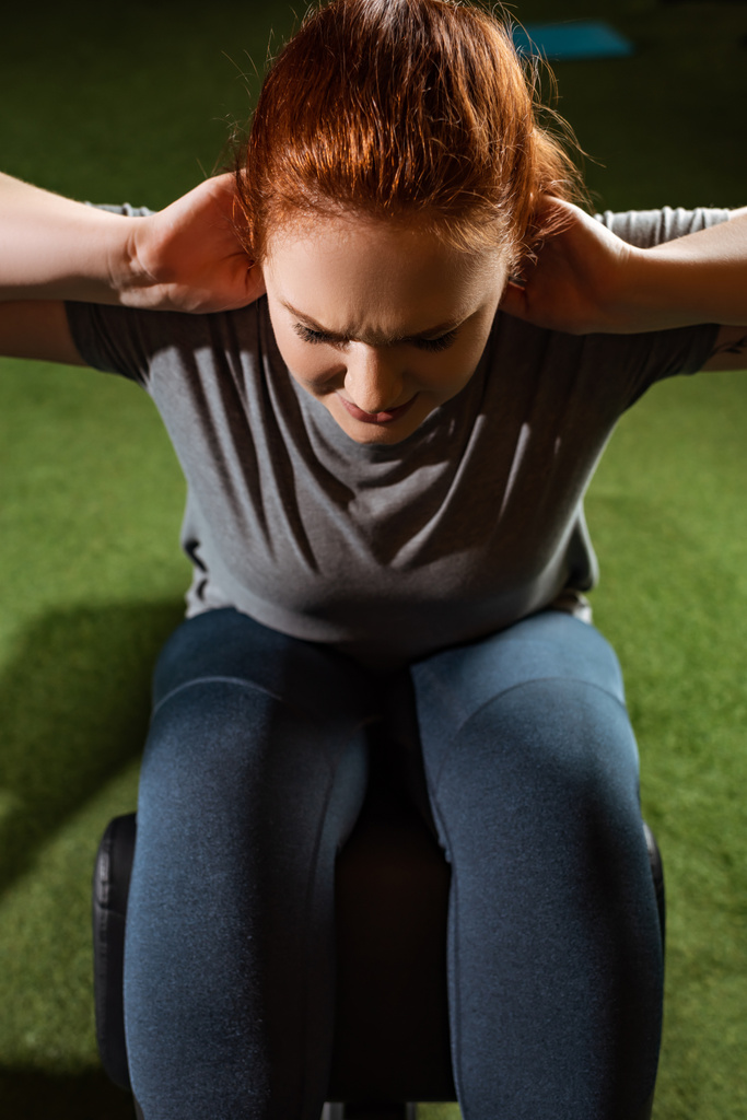 vista aérea de la chica con sobrepeso intencional haciendo ejercicio abdominales en la máquina de fitness
  - Foto, imagen
