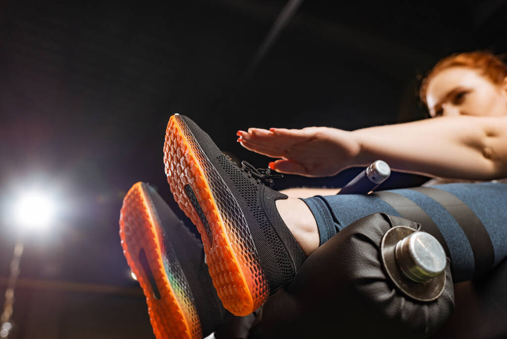 χαμηλή γωνία άποψη του υπέρβαρου κορίτσι κάνει κοιλιακούς άσκηση στο μηχάνημα γυμναστικής  - Φωτογραφία, εικόνα