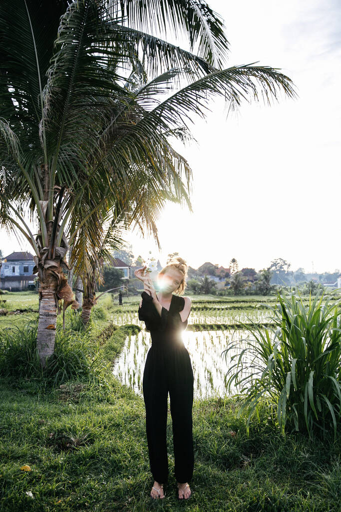 ブロンドブロガーの女の子はバリ島にインドネシア旅行中に田んぼでヨガと瞑想をしています - 写真・画像
