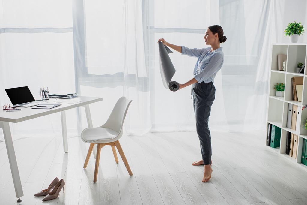 bela jovem empresária segurando tapete de ioga no escritório
 - Foto, Imagem