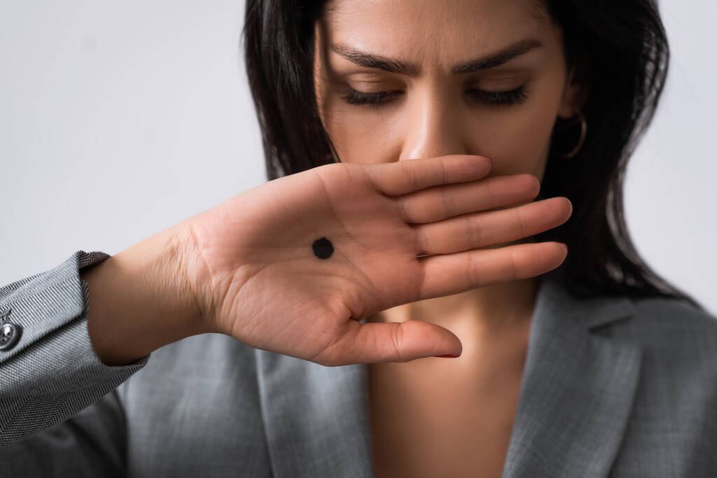 zdenerwowany bizneswoman z czarną kropką na dłoni pokrycie usta izolowane na białym, przemocy domowej koncepcji  - Zdjęcie, obraz