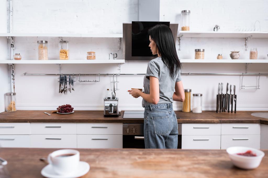 enfoque selectivo de la mujer que sostiene la placa con pan tostado y de pie en la cocina
  - Foto, Imagen