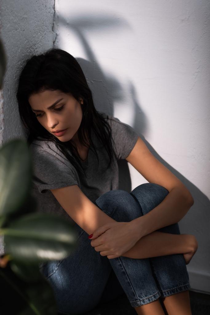 valikoiva painopiste järkyttynyt nainen mustelma kasvoilla istuu lattialla kotona, perheväkivallan käsite
  - Valokuva, kuva