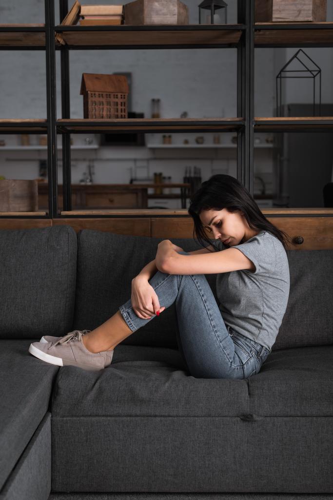 depressziós nő zúzódásokkal az arcán ül a kanapén a nappaliban, családon belüli erőszak fogalma  - Fotó, kép