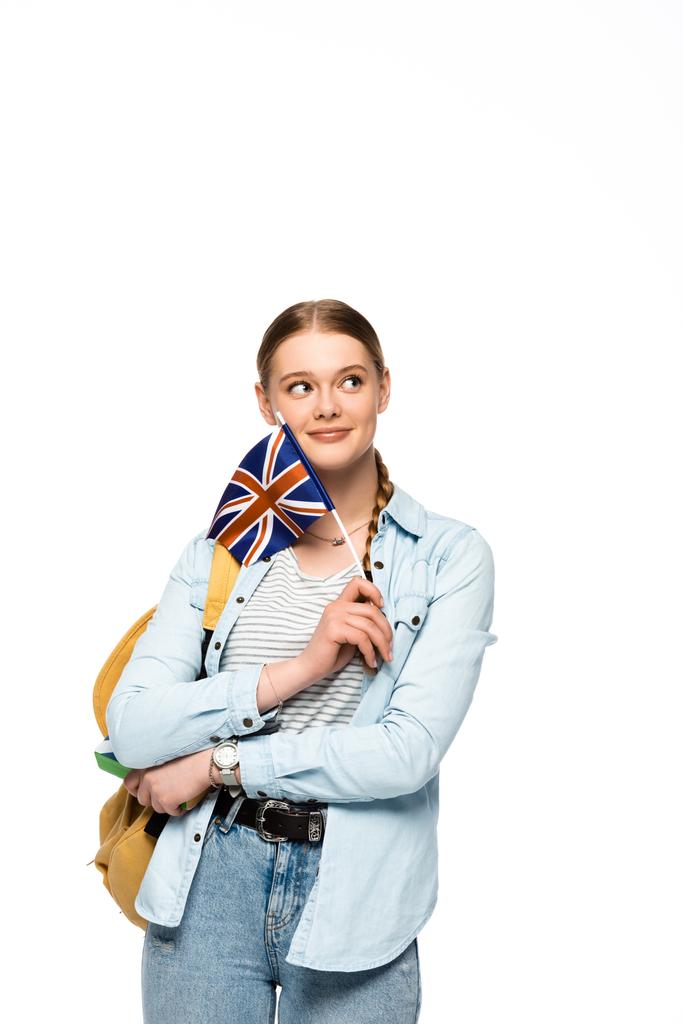 мечтательная красивая студентка с рюкзаком с книгой в руках и британским флагом, изолированным на белом
 - Фото, изображение