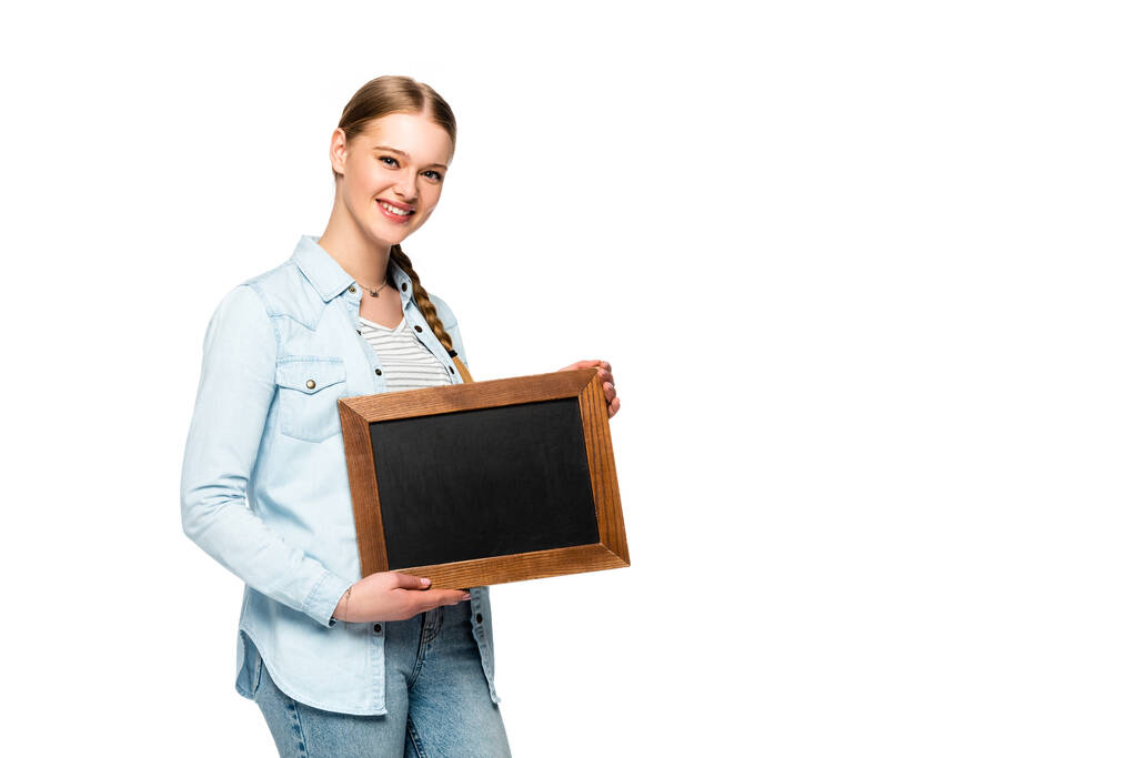 glimlachend mooi meisje met vlecht houden leeg schoolbord geïsoleerd op wit - Foto, afbeelding