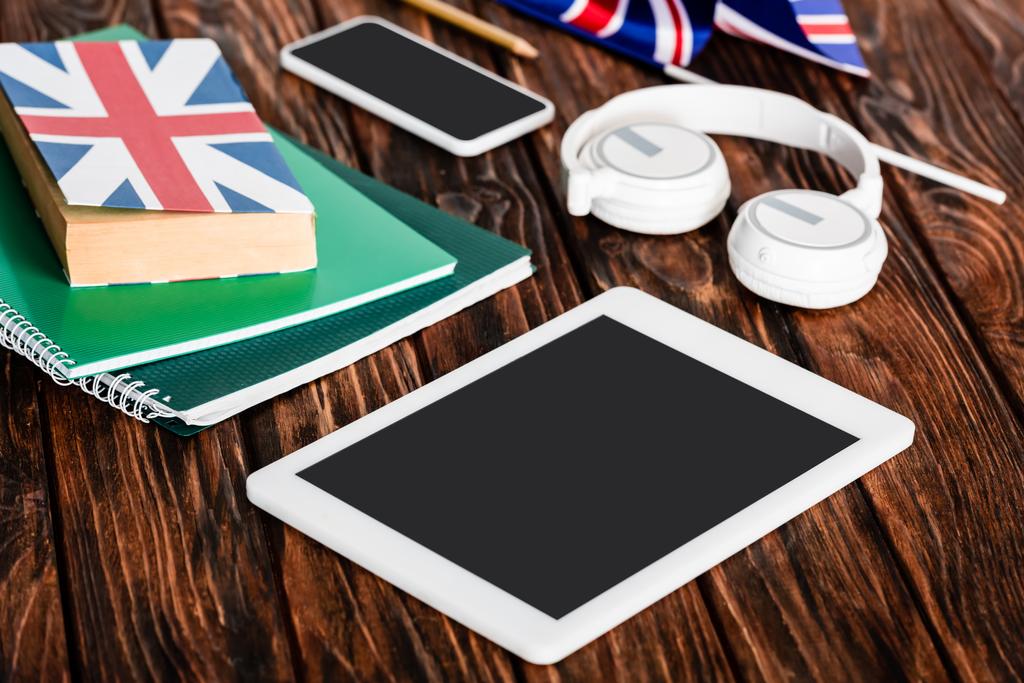Gadgets in der Nähe von Werbebüchern und Büchern mit UK-Flagge auf Holztisch - Foto, Bild