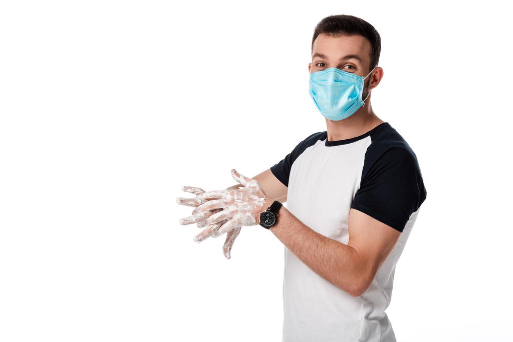 άνθρωπος με ιατρική μάσκα πλύνει τα χέρια και στέκεται απομονωμένος σε λευκό  - Φωτογραφία, εικόνα