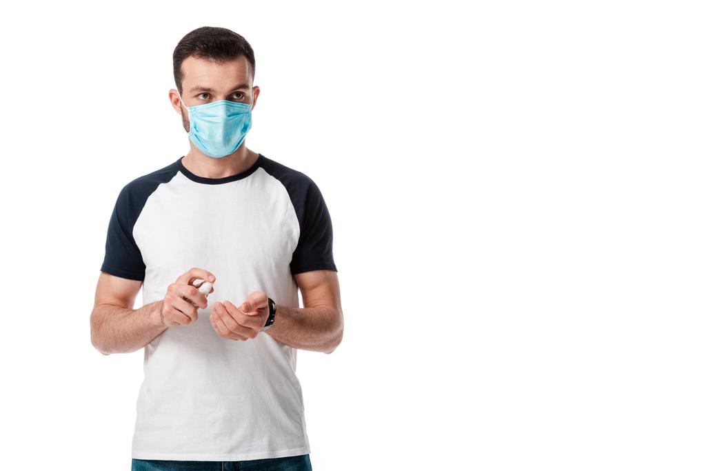 hombre en máscara médica que sostiene la botella del aerosol con el desinfectante de la mano aislado en blanco
  - Foto, Imagen