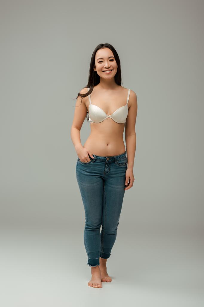 happy overweight asian woman standing with hand in pocket on grey - Photo, Image