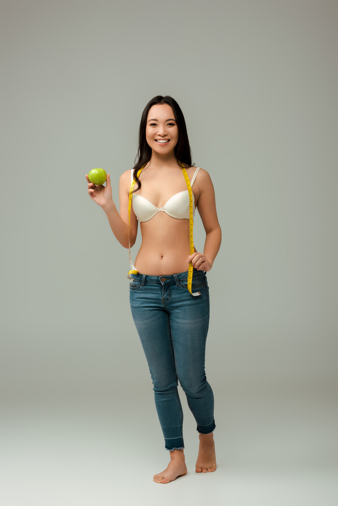 onnellinen ja ylipainoinen aasialainen tyttö tilalla mittanauha ja omena harmaa
  - Valokuva, kuva