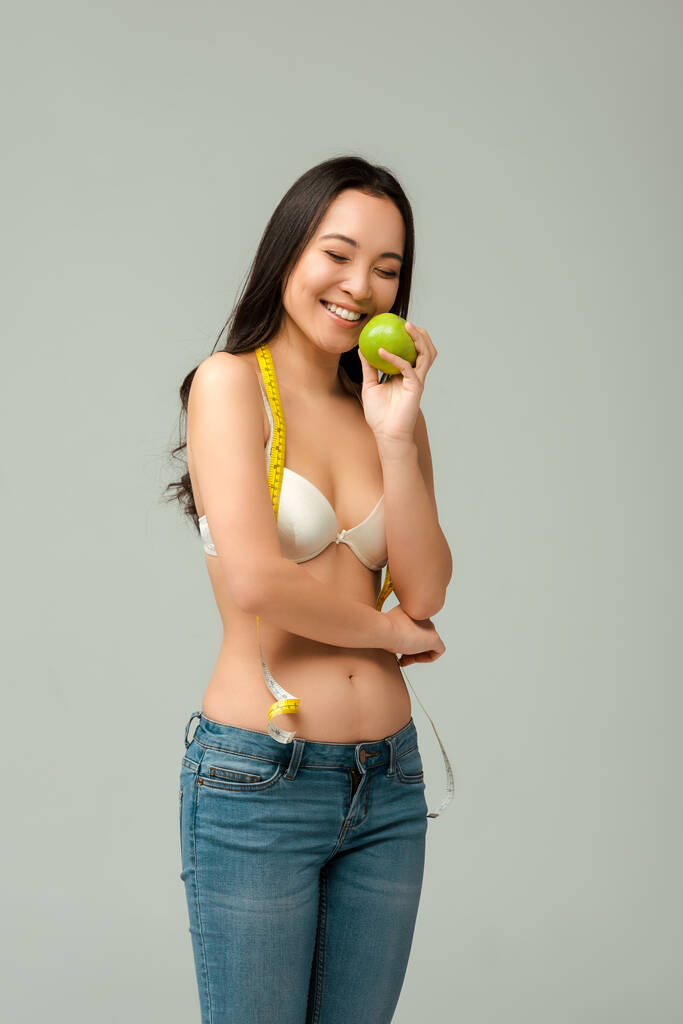 笑顔と太りすぎアジアの女の子でブラジャー保持リンゴ隔離オングレー  - 写真・画像