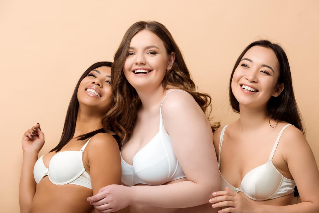 cheerful plus size multicultural women in bras isolated on beige  - Photo, Image