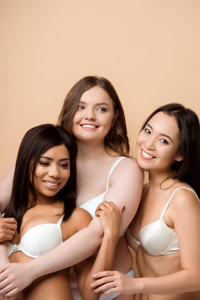 heureux plus la taille des filles multiculturelles en soutiens-gorge câlins isolés sur beige
  - Photo, image