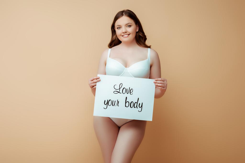 happy plus size girl mit plakat mit love your body schriftzug isoliert auf beige, body positive concept  - Foto, Bild