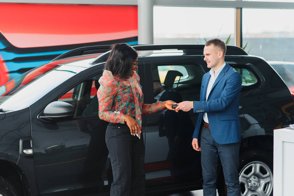 beautiful young african woman buying a car at dealership - Photo, Image