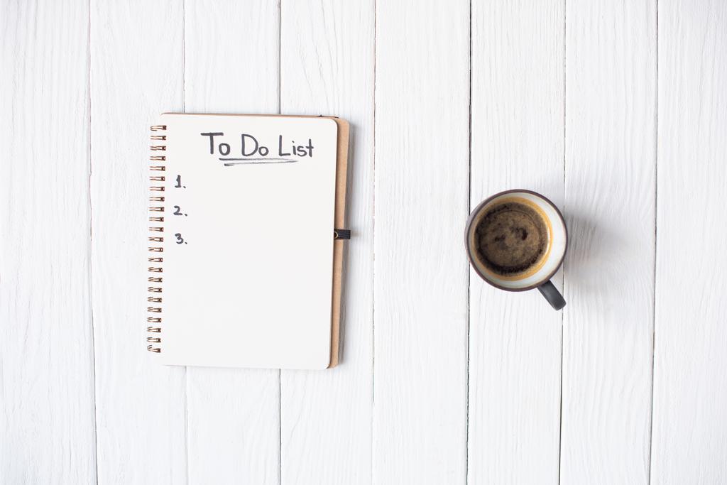 Draufsicht auf Notizbuch mit To-do-List-Schriftzug und Tasse Kaffee auf Holzgrund - Foto, Bild