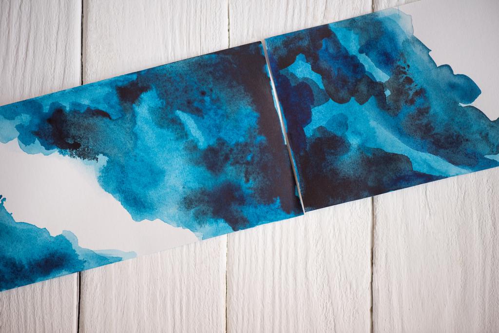 Top view of pictures with Japanese painting with blue watercolor on wooden background - Photo, Image