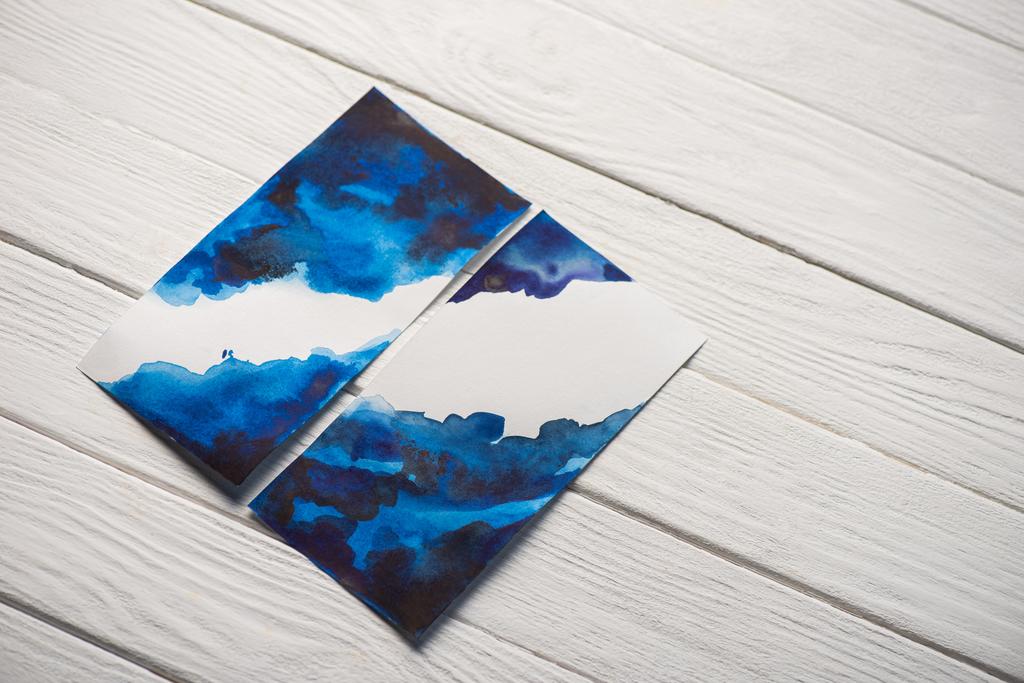 Hoge hoek uitzicht op papier met Japanse schilderkunst met felblauwe aquarel op houten achtergrond - Foto, afbeelding