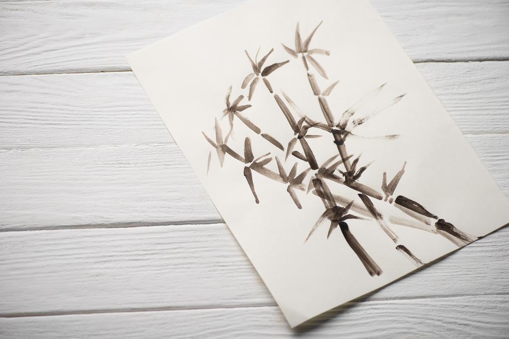 Bovenaanzicht van papier met Japanse schilderkunst met bamboe op houten ondergrond - Foto, afbeelding