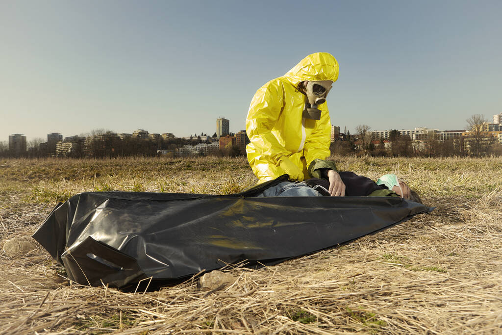 Muž v ochranných oblecích připravuje oběť nemoci k přepravě - Fotografie, Obrázek