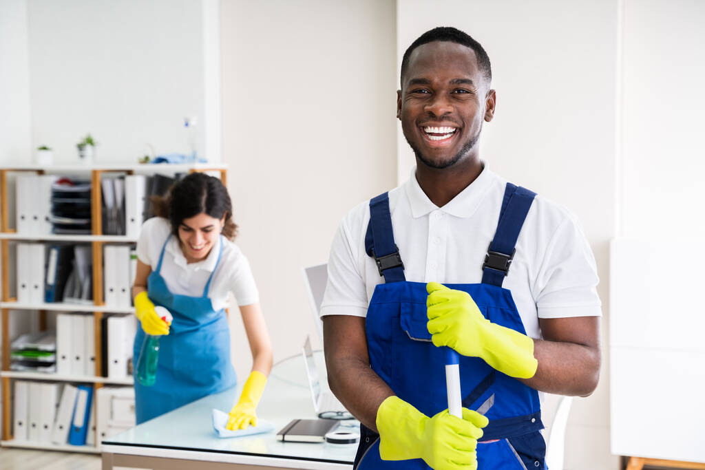 Retrato de un conserje masculino feliz con equipo de limpieza en la oficina
 - Foto, imagen