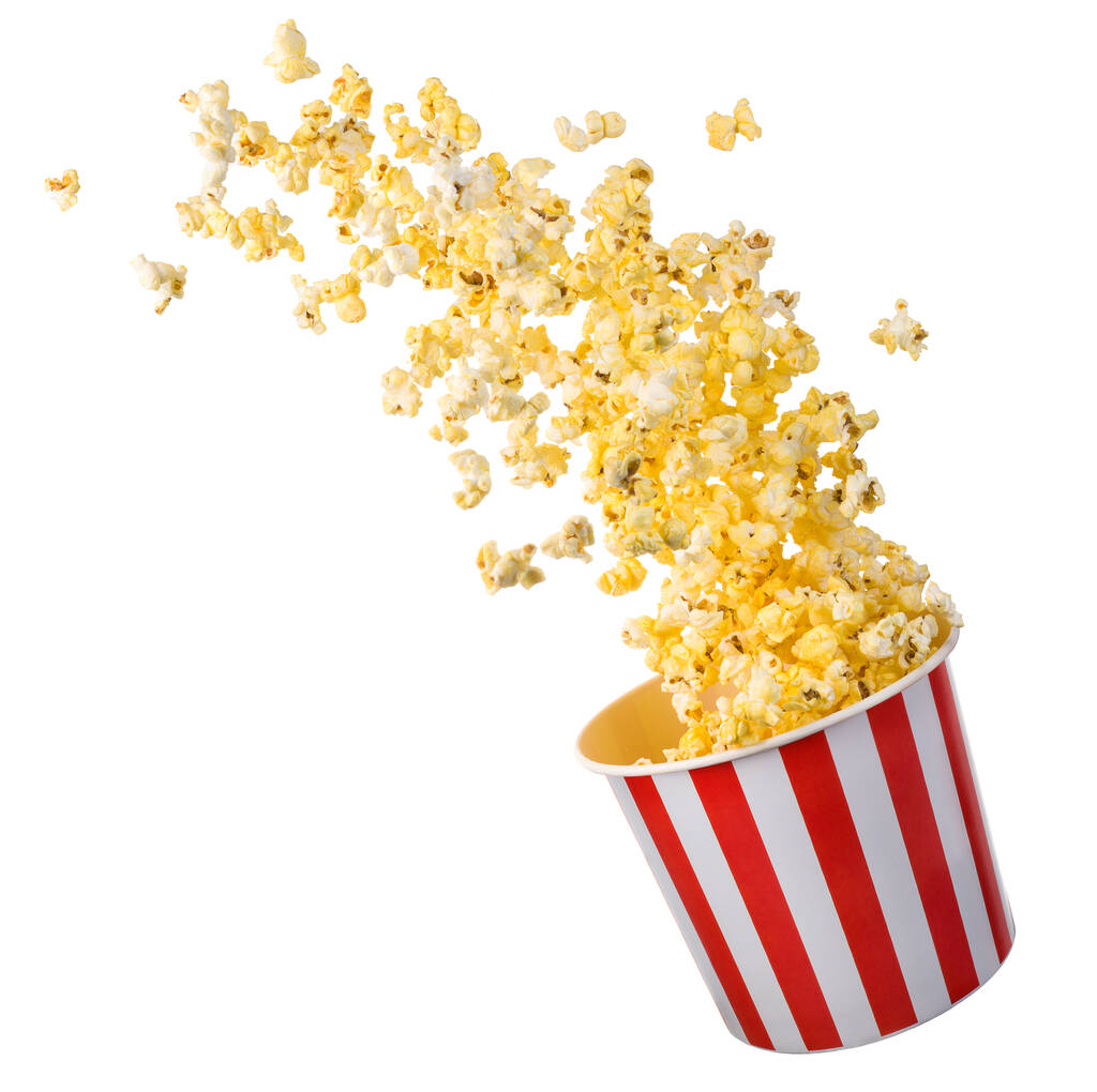 Flying popcorn from paper striped bucket isolated on black background with clipping path. Concept of cinema or watching TV. - Photo, Image