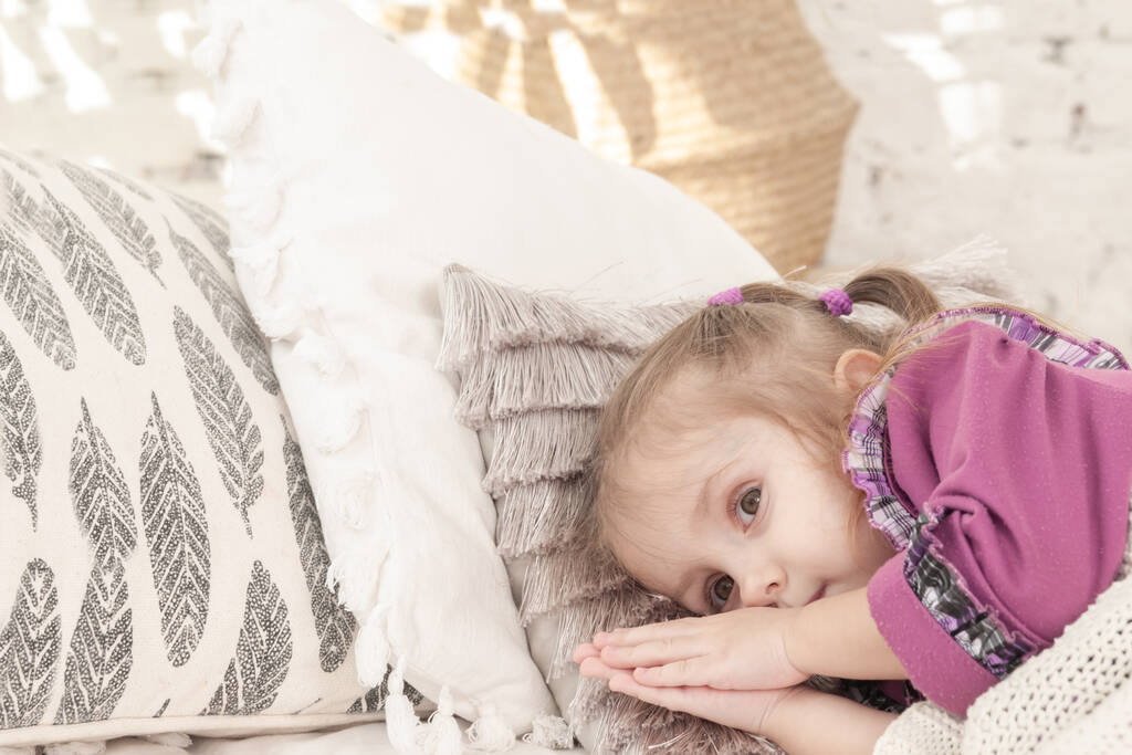 маленька усміхнена трирічна дівчинка лежить на ліжку і намагається заснути, радісно
 - Фото, зображення