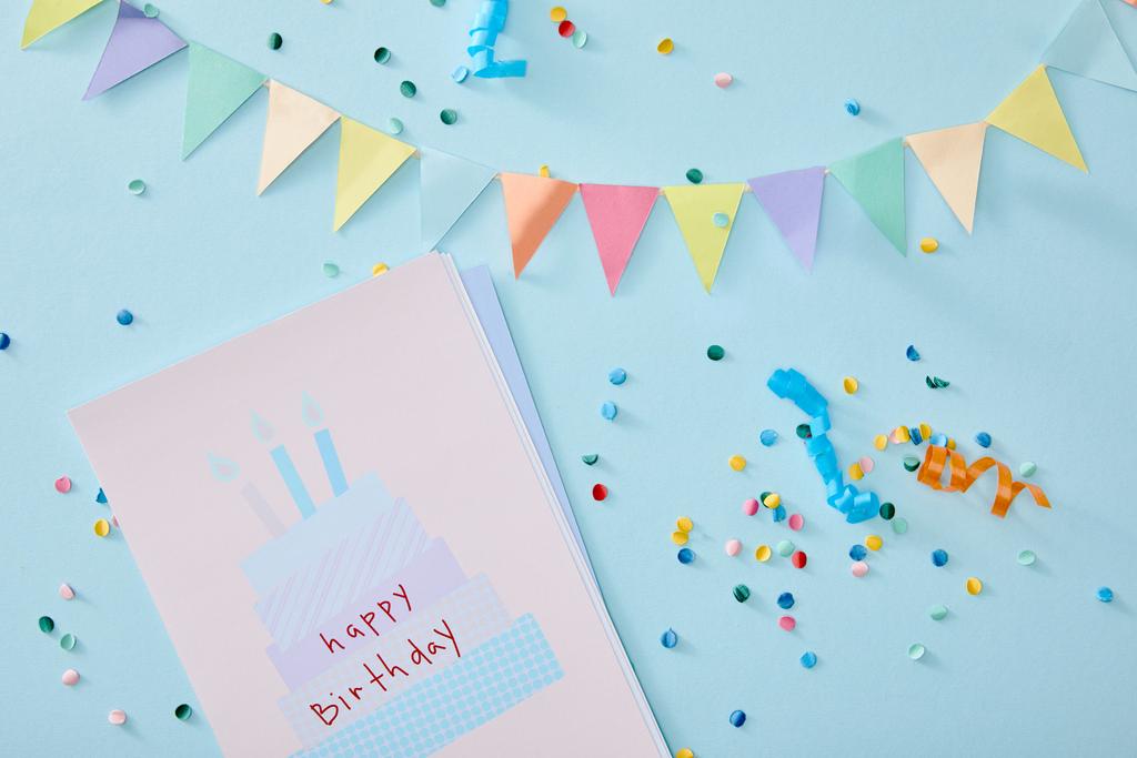 top view of colorful confetti near birthday greeting card on blue background - Photo, Image
