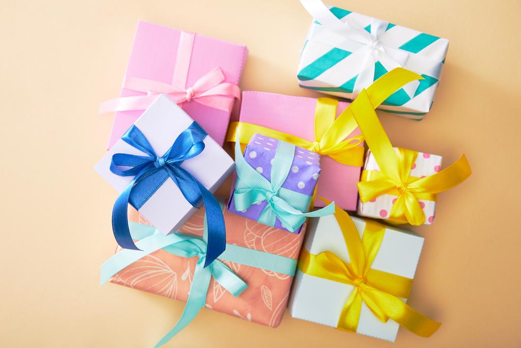 bovenaanzicht van feestelijke kleurrijke geschenkdozen op beige achtergrond - Foto, afbeelding