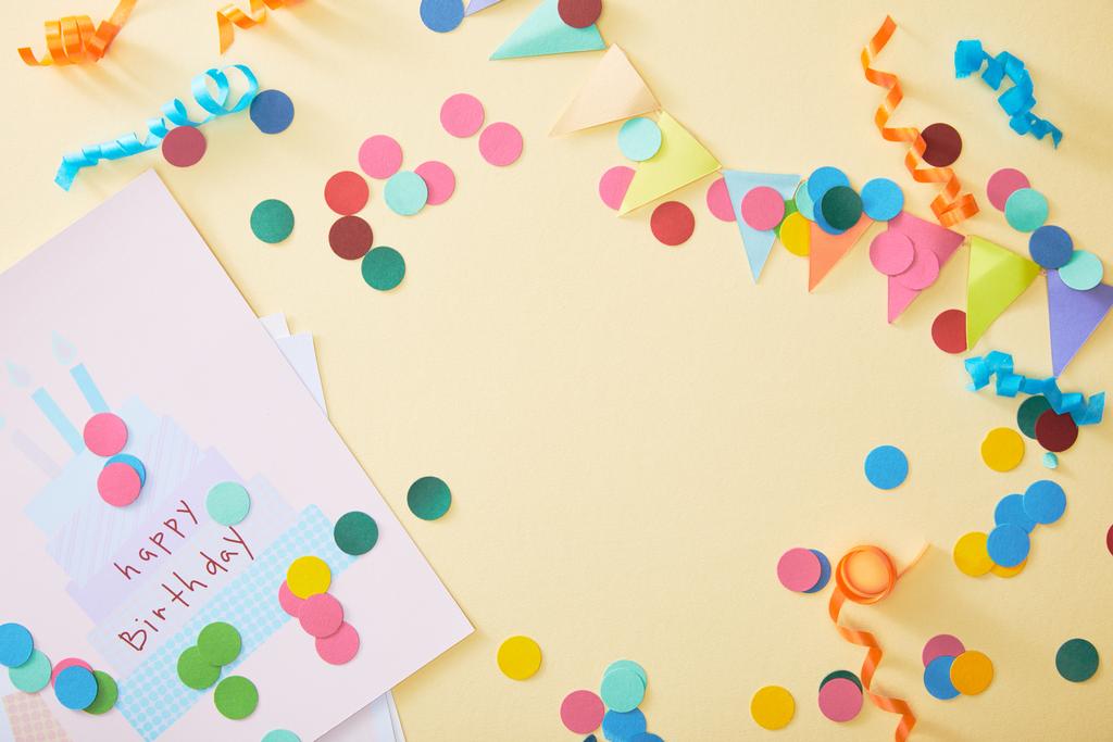 top view of festive colorful confetti and happy birthday greeting card on beige background - Photo, Image
