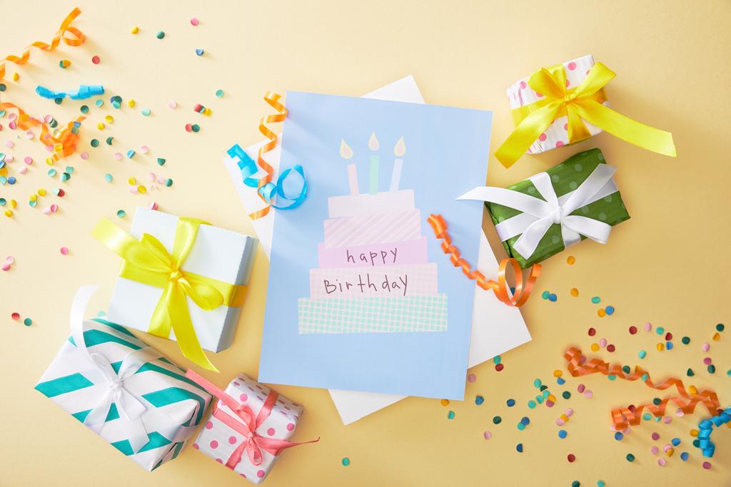 top view of festive colorful confetti, gifts and happy birthday greeting card on beige background - Photo, Image