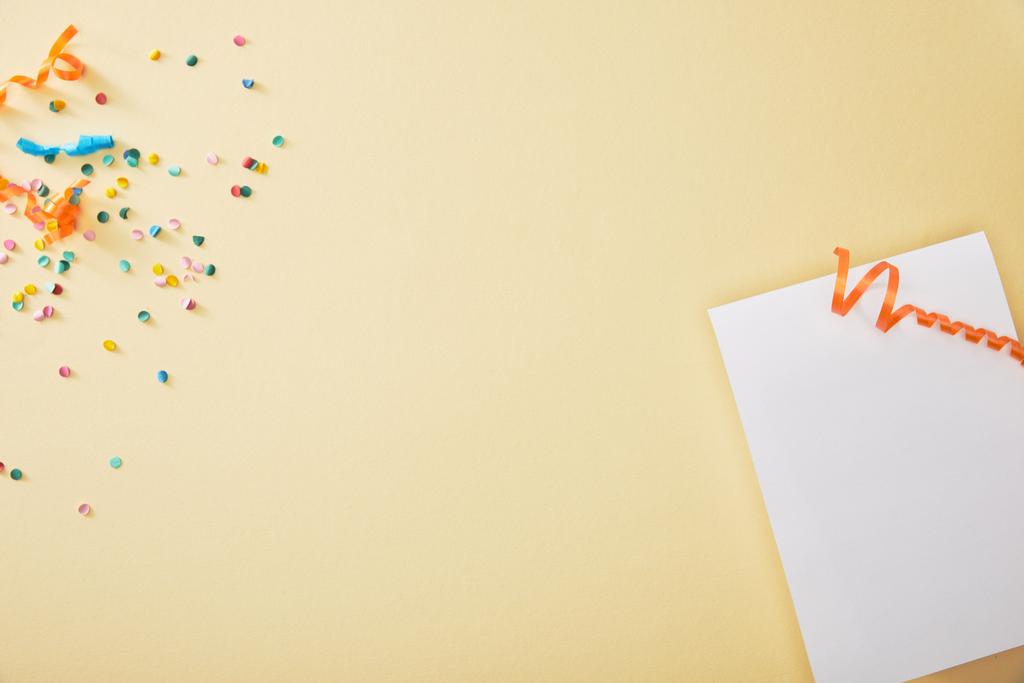 vista superior del festivo confeti colorido cerca de papel en blanco sobre fondo beige
 - Foto, imagen