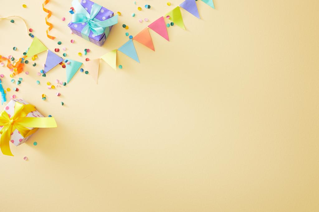 top view of festive colorful confetti and gift boxes on beige background - Photo, Image