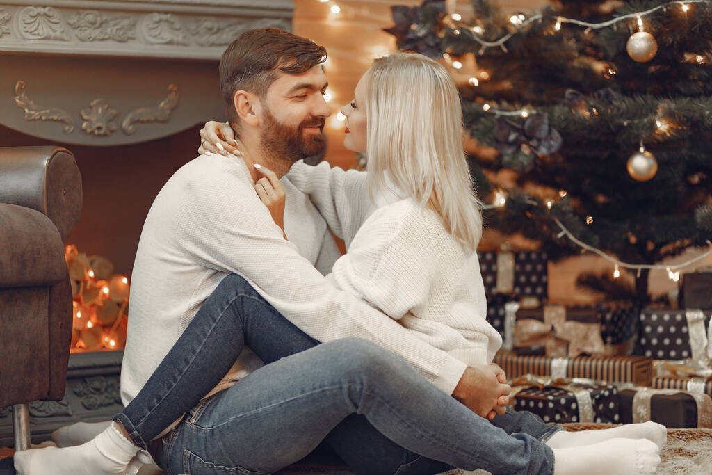 Όμορφο ζευγάρι κάθεται στο σπίτι κοντά στο χριστουγεννιάτικο δέντρο - Φωτογραφία, εικόνα