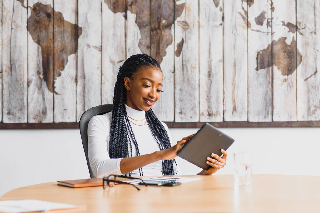 счастливая африканская бизнесвумен, использующая планшетный компьютер в офисе
 - Фото, изображение
