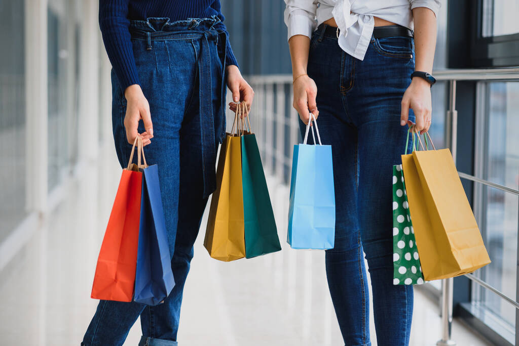 Due amiche a fare shopping passeggiando per il centro commerciale con le borse
 - Foto, immagini