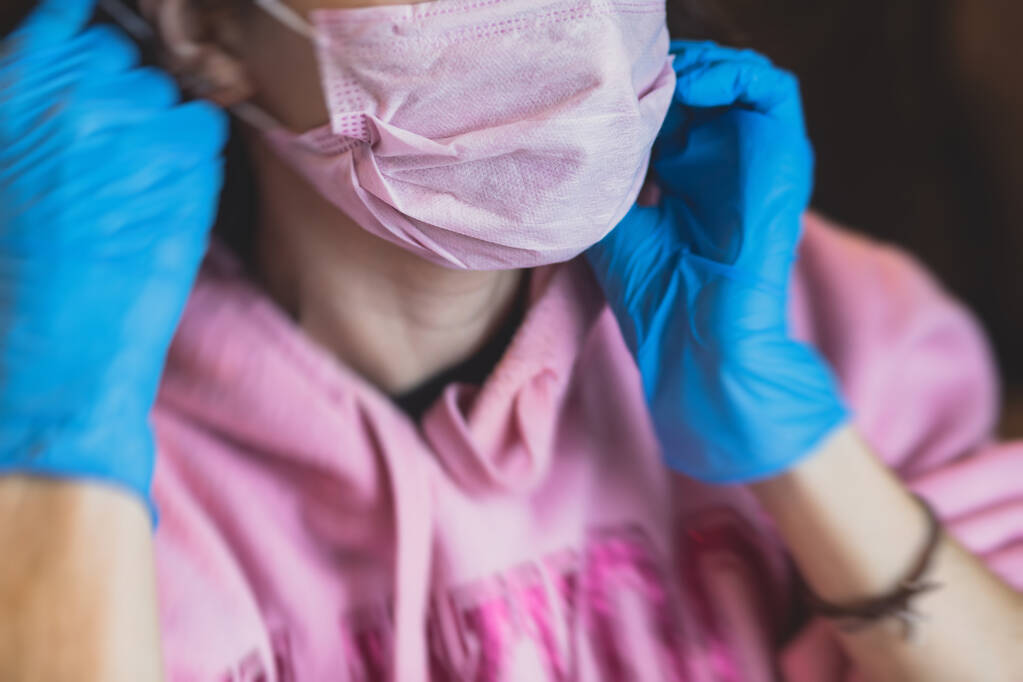 View of different coloured medical forensic face respirator mask, pink, green and blue masks. Process of wearing the mask, girl in surgical gloves wears the respirator mask - Photo, Image