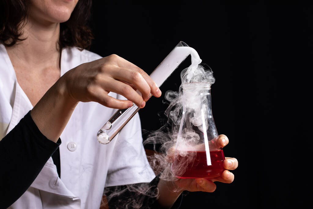 Επιστήμονας κατά τη διάρκεια μιας άσκησης χημείας όπου παράγει μια αντίδραση που αναπτύσσει λευκό καπνό - Φωτογραφία, εικόνα