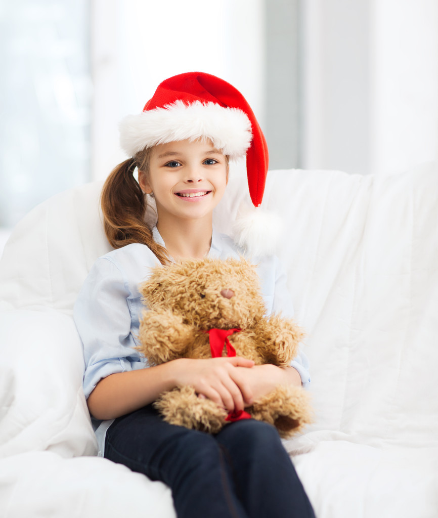 oyuncak ayı ile santa yardımcı şapkalı kız gülümseyerek - Fotoğraf, Görsel